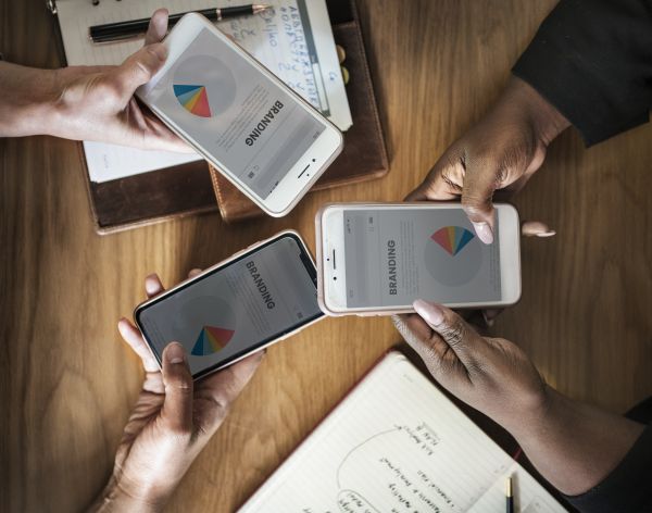 Three People Holding Phone Displaying Branding Pie Chart